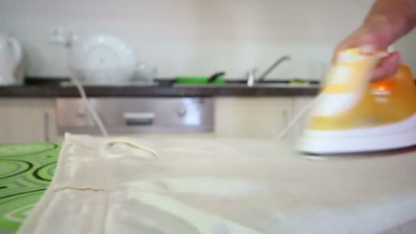 Домохозяйка гладит белье на кухне — стоковое видео