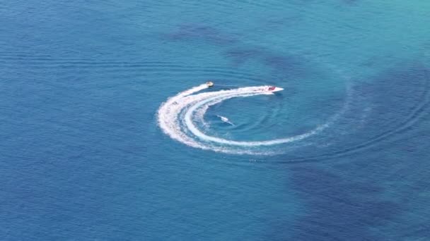 Моторная лодка буксирует надувное кольцо с отдыхающими — стоковое видео