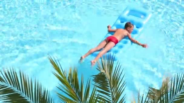 Menino flutua no colchão inflável na piscina — Vídeo de Stock