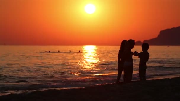 Drie kinderen praten op avond strand — Stockvideo