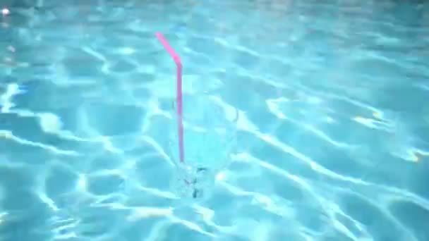 Verre avec flotteurs de paille de soda dans la piscine — Video