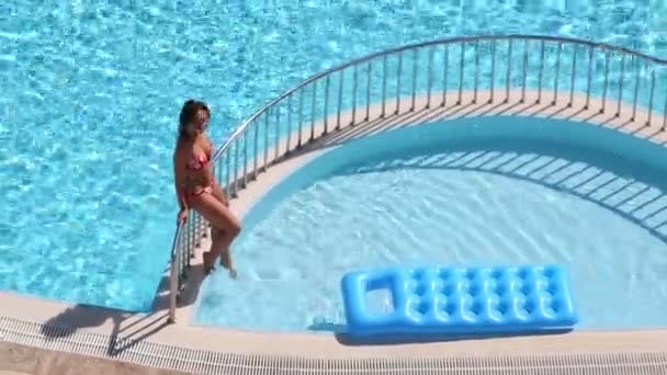 Симпатичная девушка в купальнике сидит на перилах — стоковое видео
