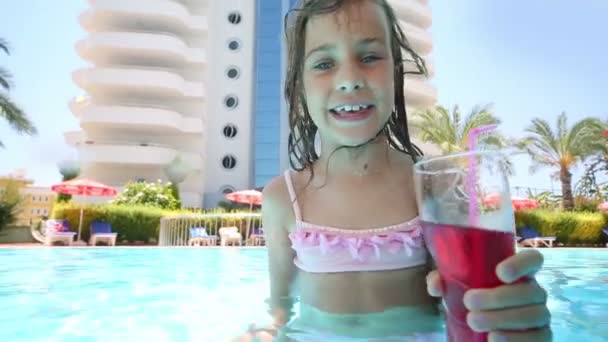 Little girl drinks cocktail in pool — Stock Video