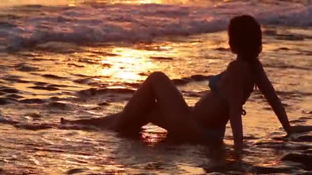 Coucher de soleil, femme assise sur du sable mouillé — Video