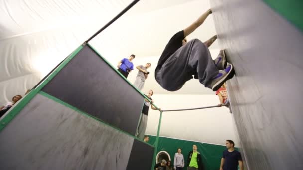 Молодой человек прыгает с одной стены на другую — стоковое видео