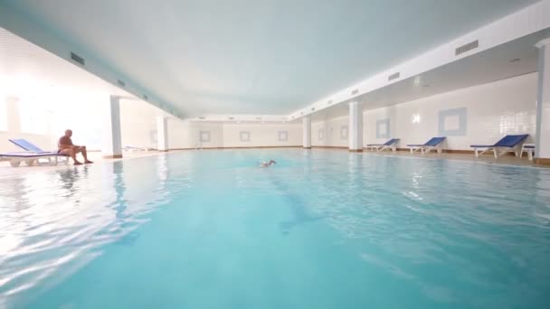 Boy swims underwater in indoor pool — Stock Video