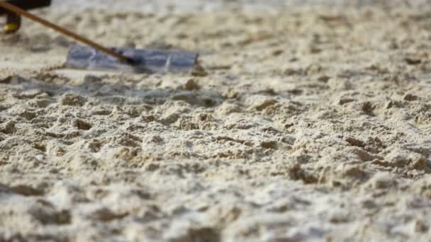 Mensen afvlakken zand oppervlak op strand — Stockvideo