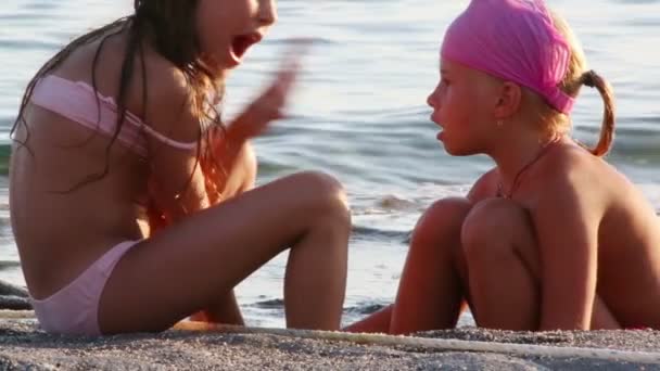 Deux petites filles s'assoient sur le sable — Video