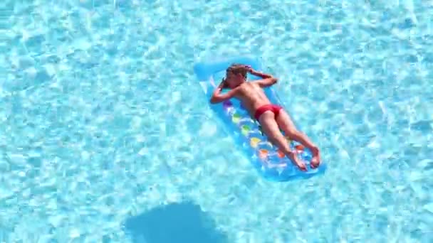 Boy floats on inflatable mattress in pool — Stock Video