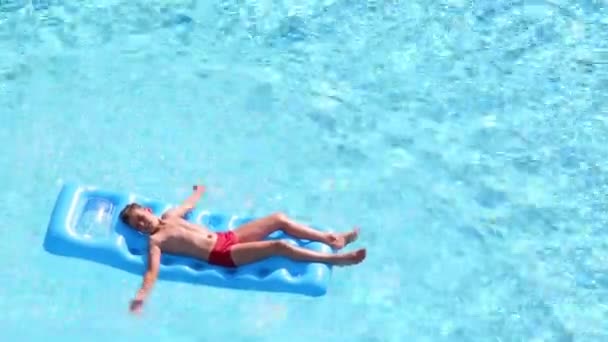 Boy floats on inflatable mattress in pool — Stock Video