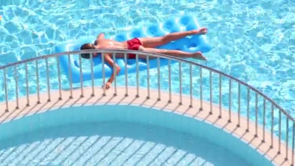 Мальчик плавает на надувном матрасе в бассейне — стоковое видео