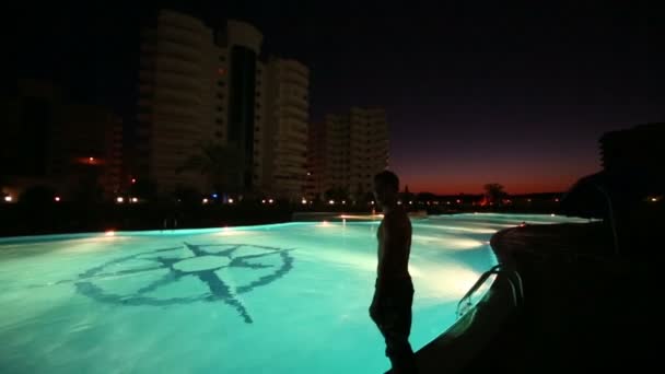 Мальчик ныряет в бассейн возле отеля — стоковое видео