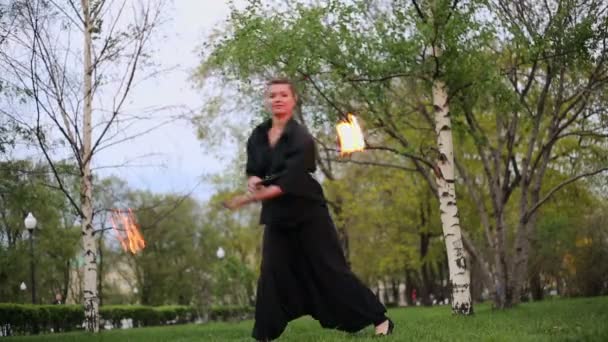 Girl in black rotates poi with flame — Stock Video