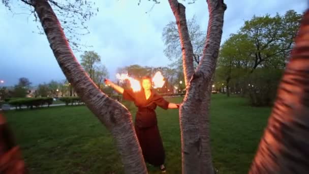 Женщина в черном вращает пои с пламенем — стоковое видео