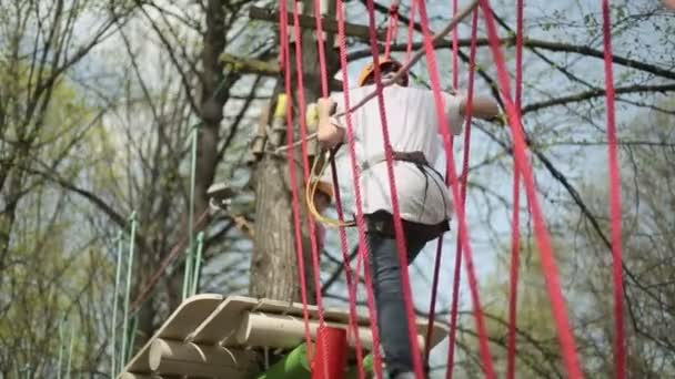 Young climber walks by log bridge — Stock Video