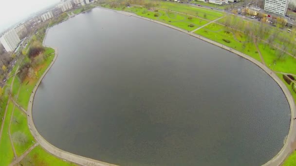 Mensen lopen door pad rond vijver — Stockvideo