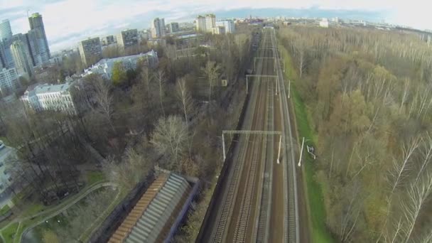 Cityscape met vier railroad tracks tussen park forest — Stockvideo