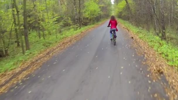 Молодая женщина на велосипеде по аллее парка, движущаяся камера — стоковое видео