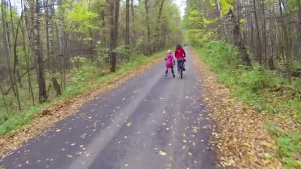 Mujer joven en bicicleta y niña en patines — Vídeo de stock