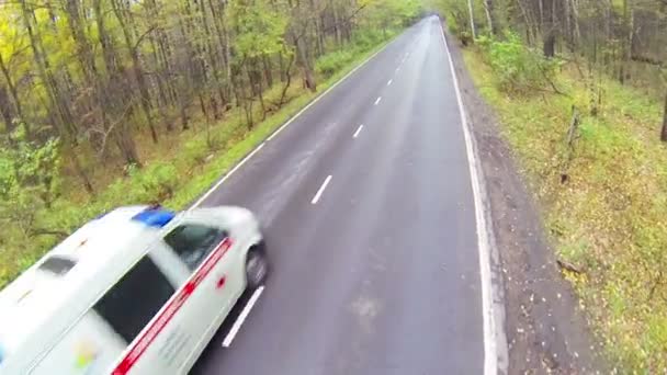 Скорая помощь на асфальтированной дороге в лесу — стоковое видео