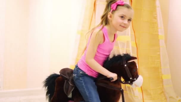 Meisje swingen op bruin schommelpaard — Stockvideo