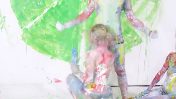 Two young women painting body of man — Stock Video
