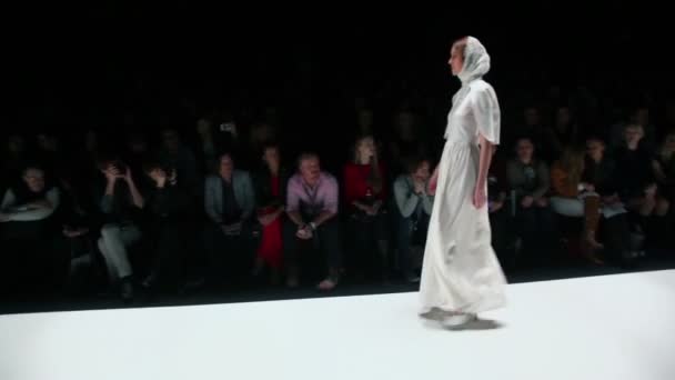 Модель в белой одежде выходит на подиум — стоковое видео