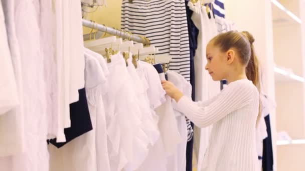 Meisje kiest kleren in winkel — Stockvideo