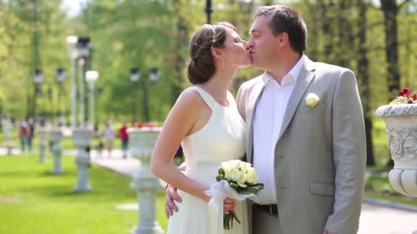 Beautiful bride with groom walk in park — Stock Video