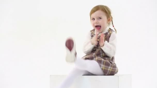 Little girl sits on white cube — Stock Video