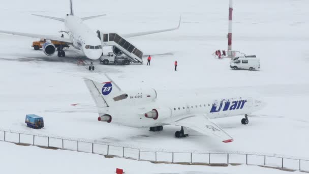 Aviones y maquinaria de servicio en aeródromo nevado — Vídeo de stock