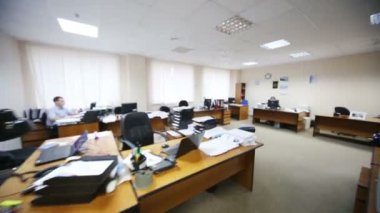İnsanlar masalarda oturup ofiste çalışırlar.
