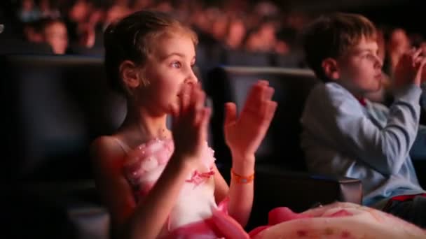 Дети аплодируют сидя в театральном зале — стоковое видео