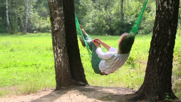 Young girl lies in hammock — Stock video