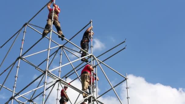 Workers in helmets working on tall scaffolding — Stock Video