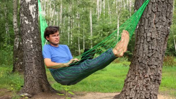 Young man lies in hammock with notebook — Stockvideo