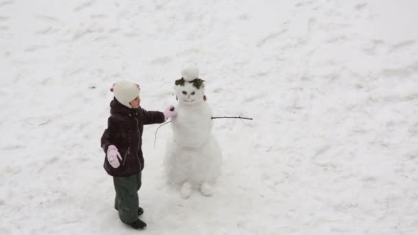 Gadis kecil bermain dengan manusia salju — Stok Video