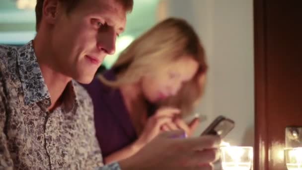 Couple sitting in restaurant with phones — Stock Video