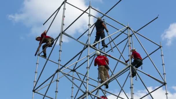 Werknemers monteren hoge structuur van buizen — Stockvideo