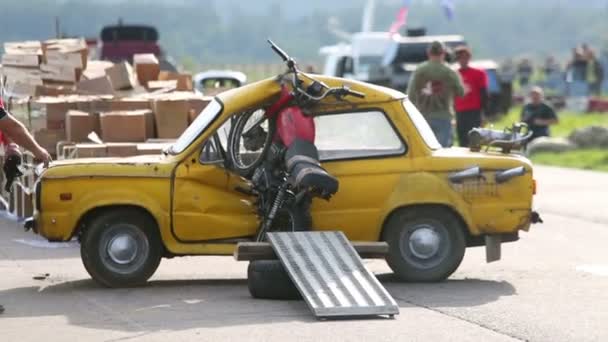 Człowiek wyciąga motocykl z uszkodzonego samochodu — Wideo stockowe