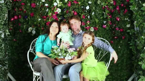 Famille assis sur un banc avec des fleurs — Video