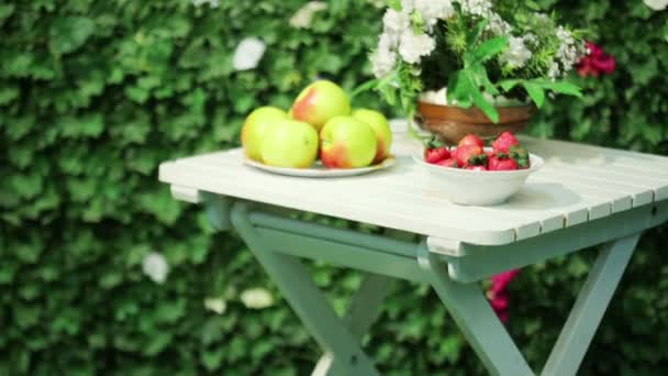 Tallrikar med äpplen, jordgubbar och blommor — Stockvideo