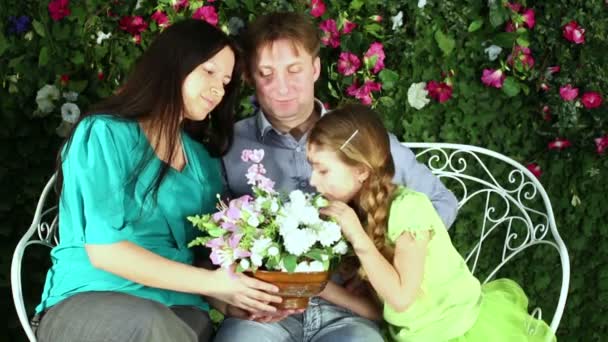 Familia de tres se sientan en el banco — Vídeos de Stock