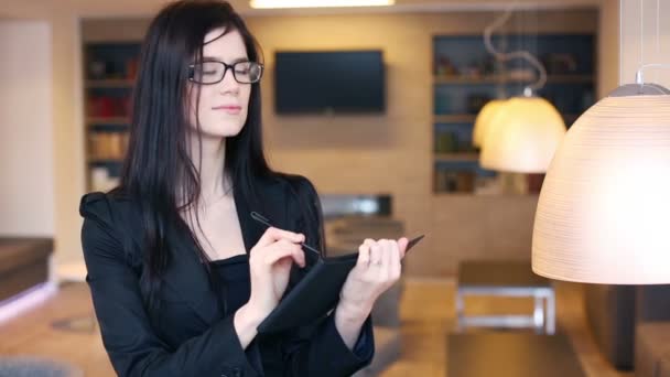 Affärskvinna i glasögon tar anteckningar i anteckningar — Stockvideo