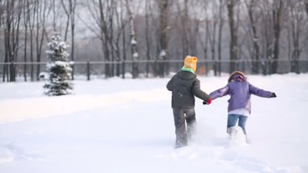 Ragazzo e ragazza cadendo in cumulo di neve — Video Stock