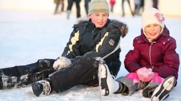 Happy boy and girl sit on ice — Stock Video