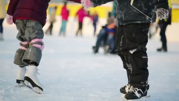 Ноги хлопчика і дівчинки вчаться кататися на ковзанах — стокове відео
