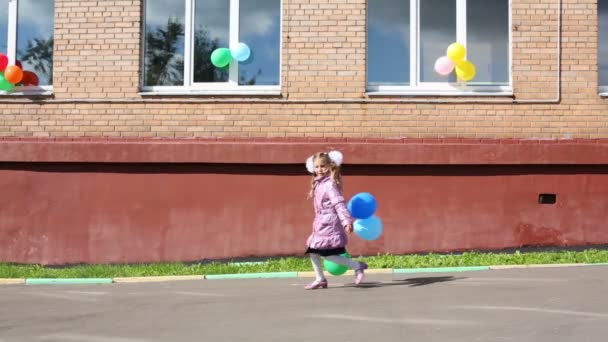 Маленька школярка біжить на шкільному подвір'ї — стокове відео