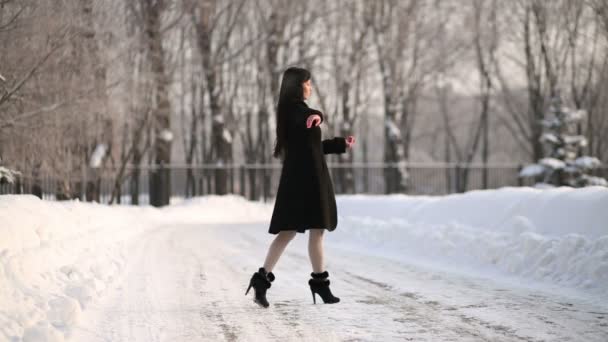 Молодая женщина в пальто крутится в танце — стоковое видео