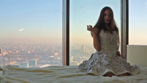 Mädchen im Kleid sitzt am Fenster — Stockvideo